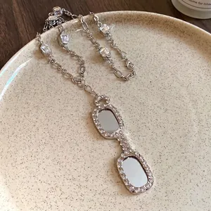 Elegant silver eyeglass pendant necklace with sparkling zircon accents on ceramic plate