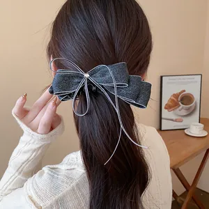 Detailed back view showing an elegant sparkling bow hair clip in long wavy brunette hair