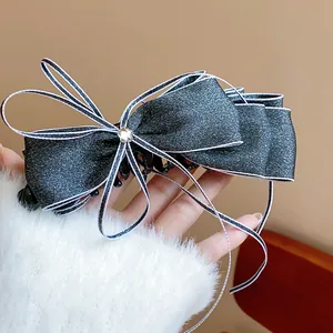 Detailed macro view of elegant black bow banana hair clip featuring white ribbon edges