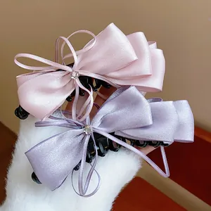 Close-up of elegant satin ribbon bow banana clips in pink and lavender.