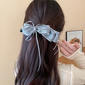 Elegant grey sparkly bow banana clip with thin ribbons worn on wavy brown hair
