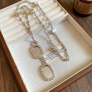 Macro detail of a silver eyeglasses pendant necklace with sparkling stones in a wooden box