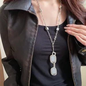 Close-up of a silver-tone necklace with a rhinestone-studded eyeglasses pendant.