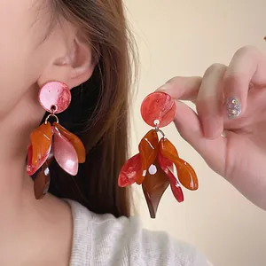 Close-up of vintage resin petal dangle earrings shown on ear and held by hand.