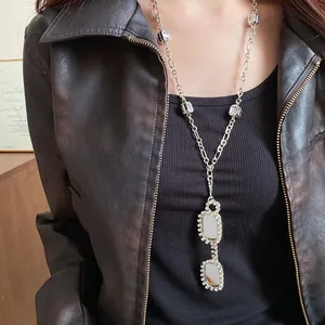Close-up of a trendy silver necklace featuring a zircon-studded sunglasses pendant.