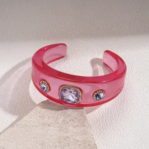 Translucent pink resin cuff bracelet featuring three embedded purple faux gemstones.