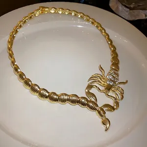 Statement gold plated choker necklace featuring a rhinestone encrusted scorpion design