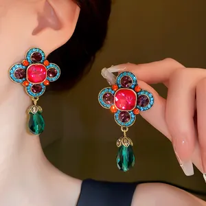 Primo piano di orecchini floreali in stile palazzo con pendenti a goccia verdi.