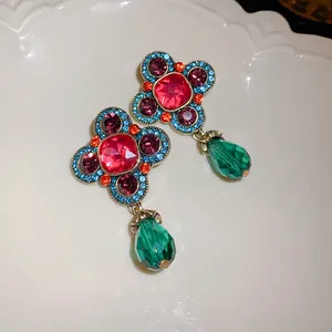 Dettaglio di orecchini vintage stile palazzo con strass colorati e gocce verdi smeraldo