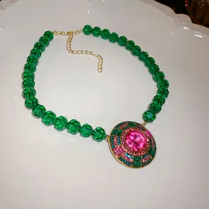 Dettaglio di una collana vintage in stile palazzo con perline verdi e pietra rosa
