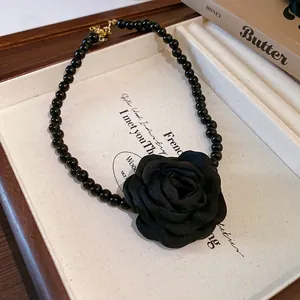 Close-up of French style black fabric rose necklace with beaded chain on display box