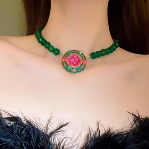 Primo piano di una collana di perle verdi stile vintage con ciondolo rosa