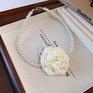 Detail view of elegant French style white fabric camellia flower pearl choker necklace