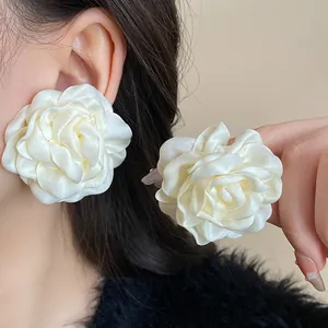 Close-up of elegant French style white fabric rose flower earrings for women