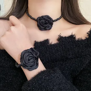 Close-up detail of elegant black fabric rose choker and matching beaded bracelet set