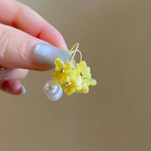 Nahaufnahme von 18K vergoldeten Ohrringen mit gelben Harzblumen und Perlen im Mori-Stil