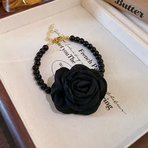 Detailed view of an elegant black fabric rose with a black beaded choker necklace.