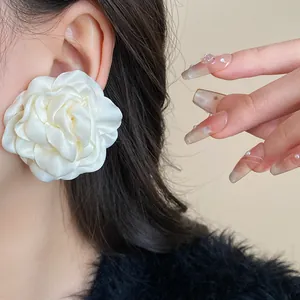Detailed macro view of a large white fabric camellia earring with satin finish.