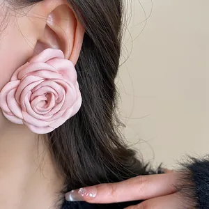 Macro view showing the delicate petals of a pink fabric rose flower earring on ear
