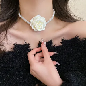 Close-up of an elegant pearl choker necklace featuring a large white fabric rose