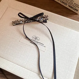 Detail showing elegant black ribbon bow hair clip with grey faceted crystal beads.