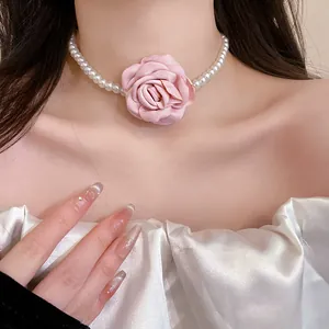 Close-up of a French style pearl choker necklace with a large pink fabric rose decoration