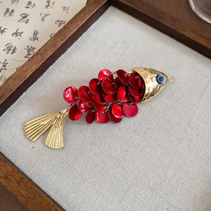 Detailed macro view of a red sequined fish-shaped hair clip with gold metal accents and blue eye