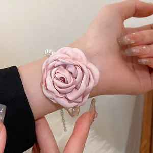 Close-up detail of a sweet pink fabric flower and elegant pearl bracelet on wrist