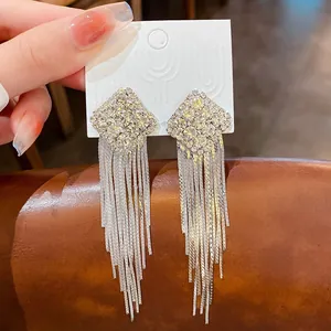 Gros plan de boucles d'oreilles à pampilles en argent et strass carrés sur carte
