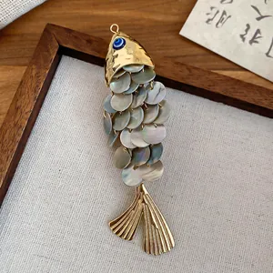 Close-up detail of fish hair clip with mother of pearl scales and evil eye accent