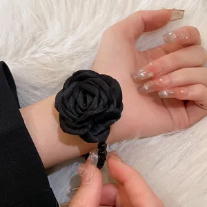 Close-up detail of a handmade black fabric rose bracelet with beaded band on wrist