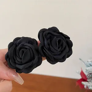 Close-up view of two elegant black fabric rose hair accessories with intricate petal details