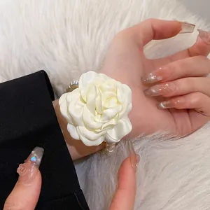 Close-up detail of a French style white fabric rose accessory with elegant pearls on wrist