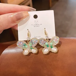 Vue macro détaillée de boucles d'oreilles papillon élégantes avec nacre et accents de fleurs