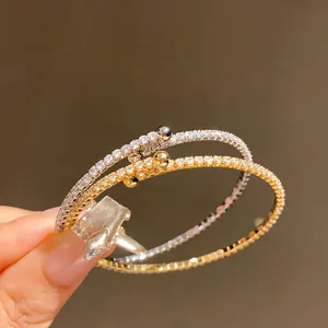 Détail de bracelets ouverts dorés et argentés ornés de zircons cubiques scintillants