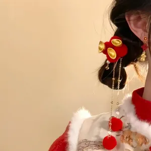 Close-up of festive red flocked hair clip with gold ingots and long tassels worn on hair