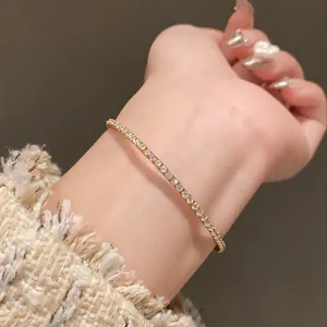 Vue détaillée d'un bracelet de tennis minimaliste en or et zircon au poignet d'une femme