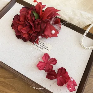 Detailed shot of an elegant red flower hair clip featuring white pearls and delicate feathers