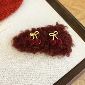Close-up detail view of red flocked cherry hair clips featuring golden twisted bow accents