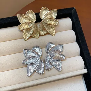 Detailed view of gold and silver petal-textured stud earrings on jewelry display