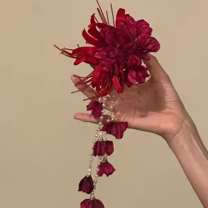 Detailed view of a red floral hair clip featuring elegant pearl and petal tassel drops.