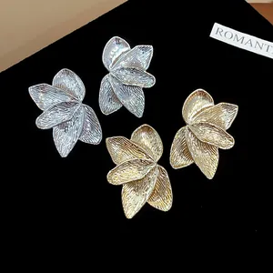Detailed view of gold and silver petal-textured stud earrings on black velvet
