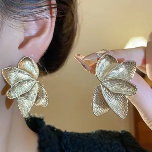 Detailed macro view of elegant golden petal texture stud earrings with a luxury matte finish