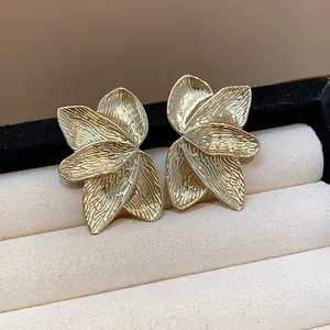 Detailed close-up of elegant gold floral petal textured stud earrings in a box