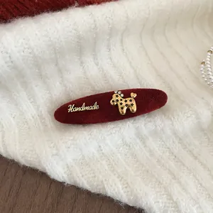 Macro shot of a red velvet duckbill hair clip with a gold poodle and Handmade charm