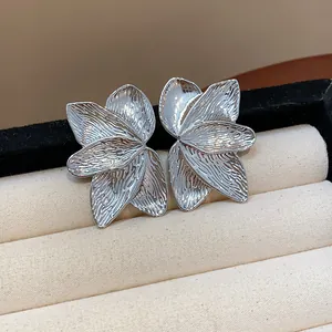 Macro view showing the intricate texture of silver petal stud earrings on display