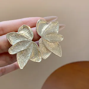 Detailed macro view of large gold flower petal earrings with intricate textures