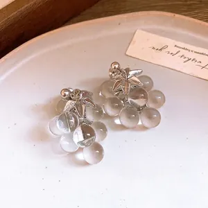 Elegant crystal grape cluster earrings with silver leaf decoration on white ceramic plate
