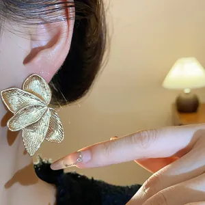 Macro view of elegant gold petal earrings showing detailed leaf texture and finish