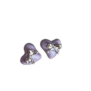 Elegante lila Herz-Ohrstecker mit silbernem Schleifen-Design auf weißem Hintergrund.